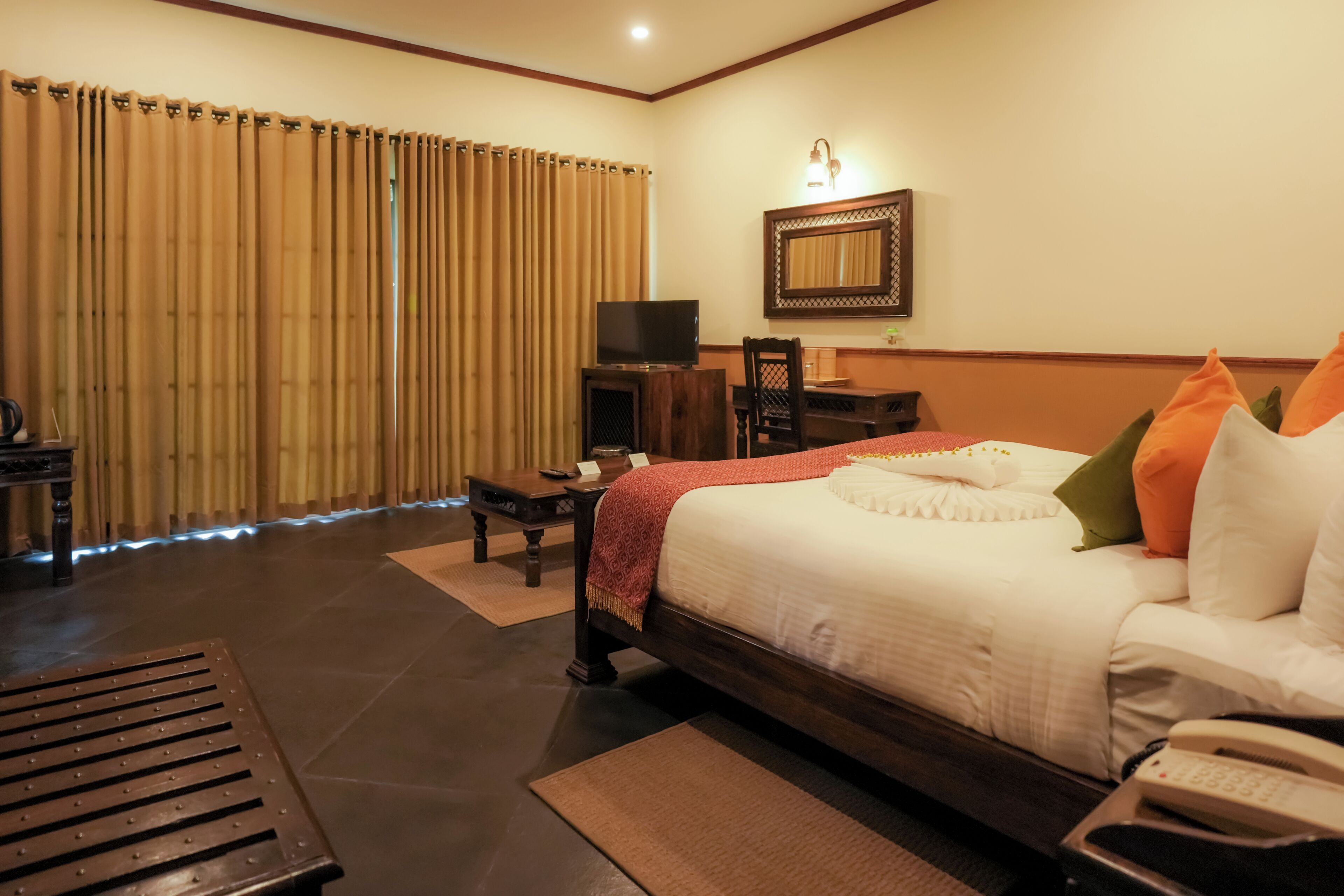 A hotel room with a bed, a desk, a television, and a telephone.