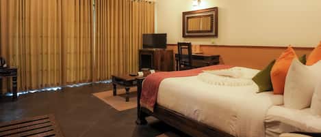 A hotel room with a bed, a desk, a television, and a telephone.