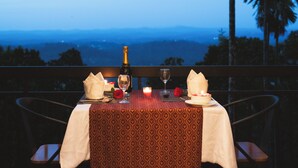 A table set for two with a bottle of champagne, a glass, a candle, and a rose. - The Hive Wayanad By Kondody Hotels (Vythiri)
