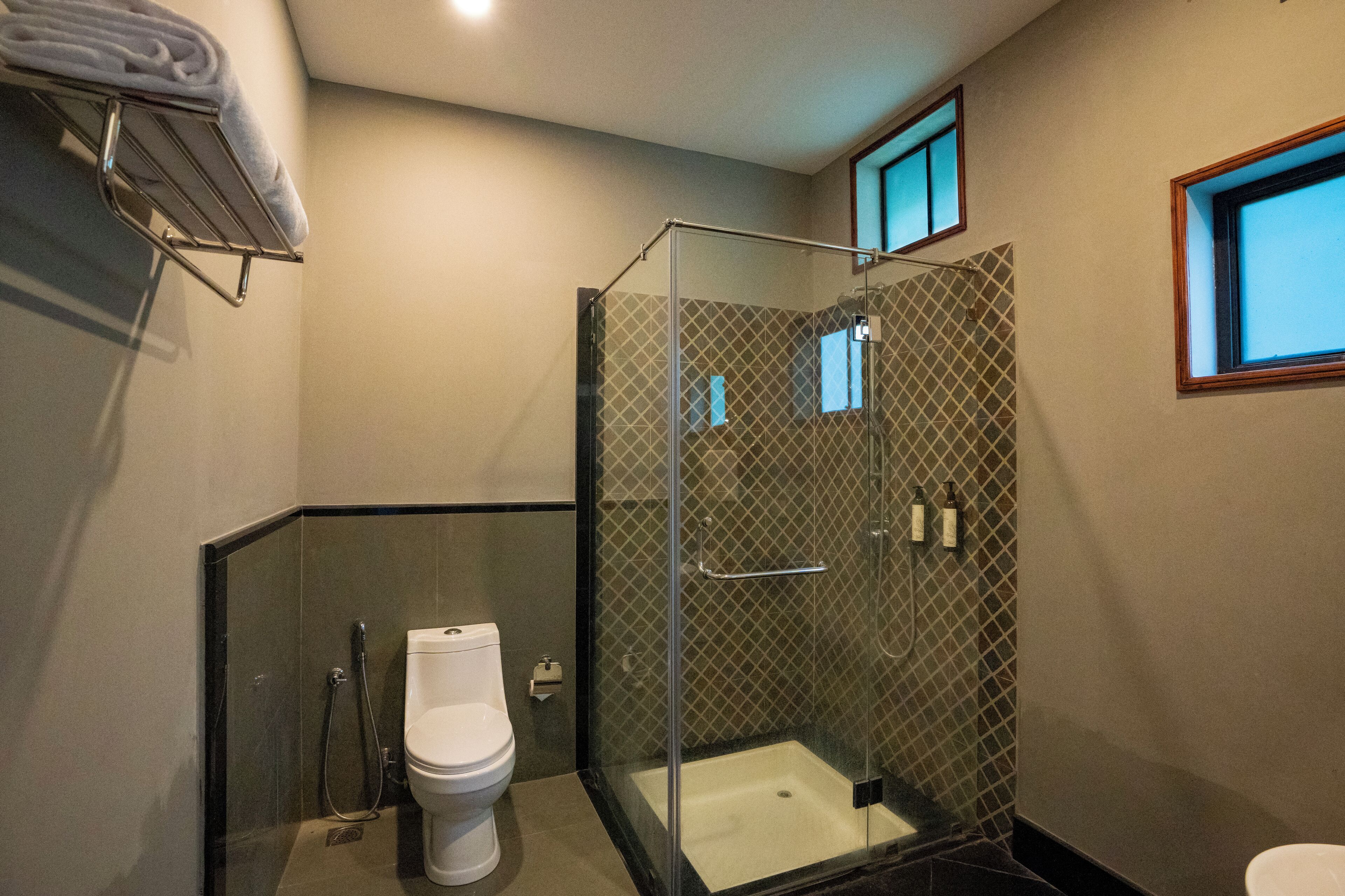Un bany modern amb dutxa de vidre, vàter i paraigua per a tovalloles.