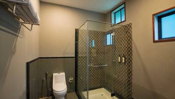 A modern bathroom with a glass-enclosed shower, a toilet, and a towel rack.