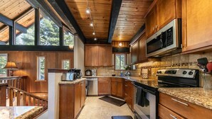 Une cuisine moderne avec des meubles en bois, des appareils électroménagers en acier inoxydable et une grande fenêtre qui laisse entrer la lumière naturelle.