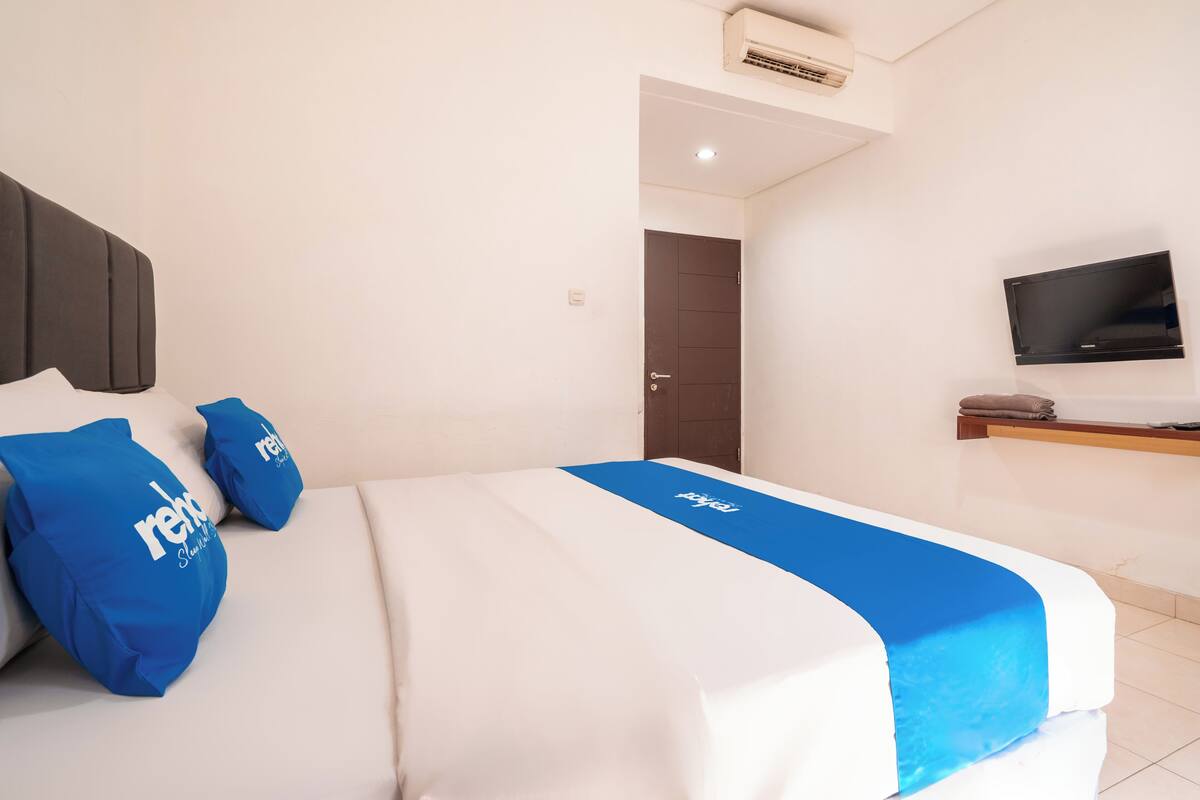 A hotel room with a bed, a TV, and a door.