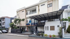 Un bâtiment moderne à deux étages doté d’un espace extérieur aménagé avec des sièges, d’un escalier et d’une entrée sécurisée par un portail.