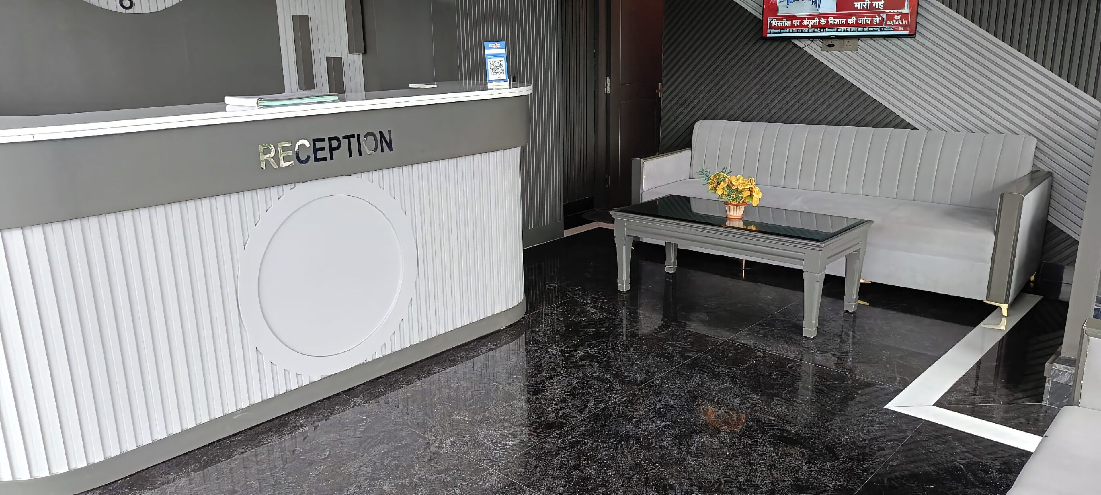A reception area with a reception desk labeled "RECEPTION," a sofa, a small table with a vase, and a tiled floor.