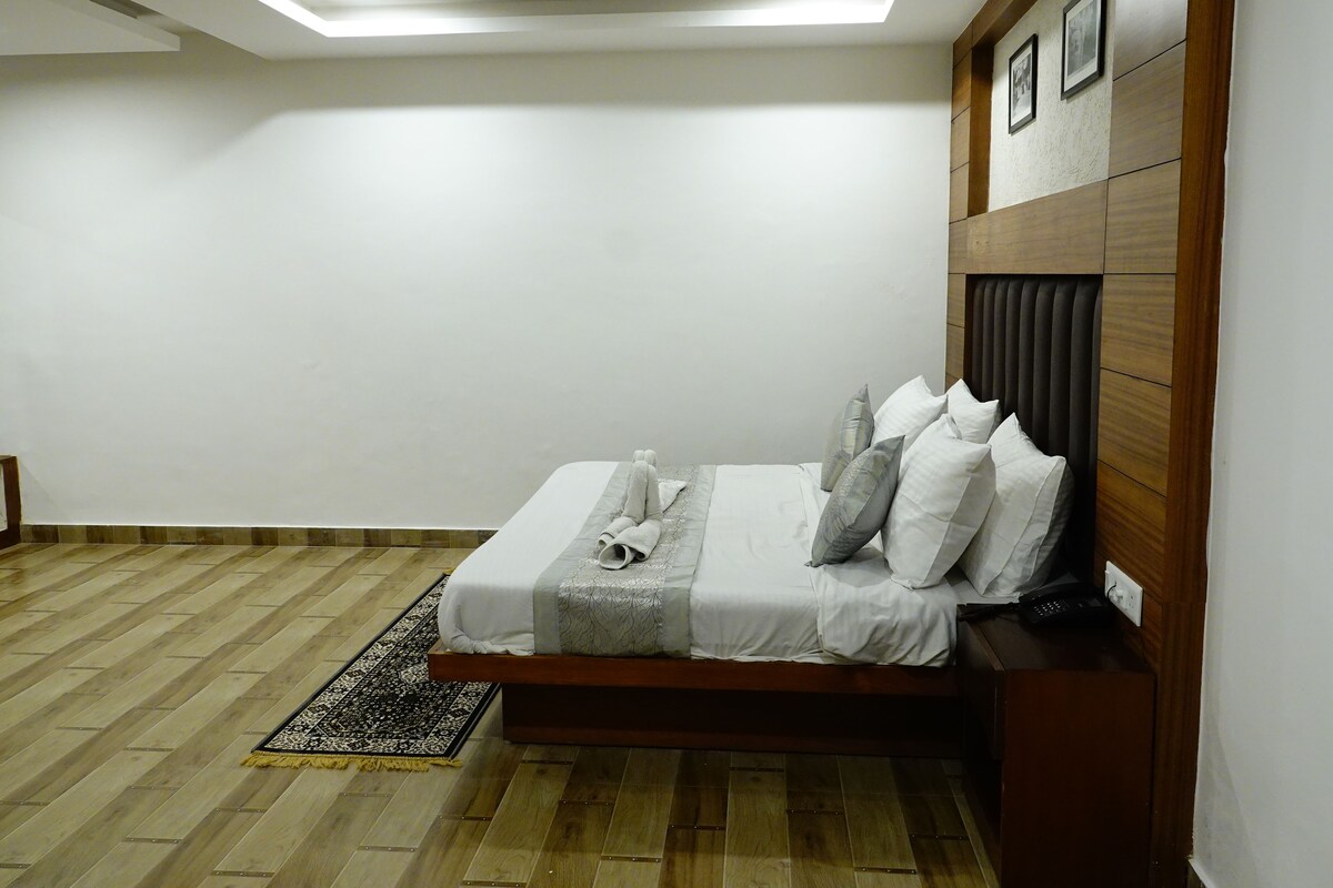A bedroom with a bed, a ceiling fan, a wooden headboard, and a patterned rug.
