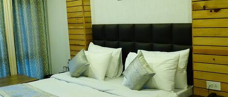 Een hotelkamer met een groot bed, een plafondventilator, een ingelijst kunstwerk aan de muur en houten paneelbekleding.