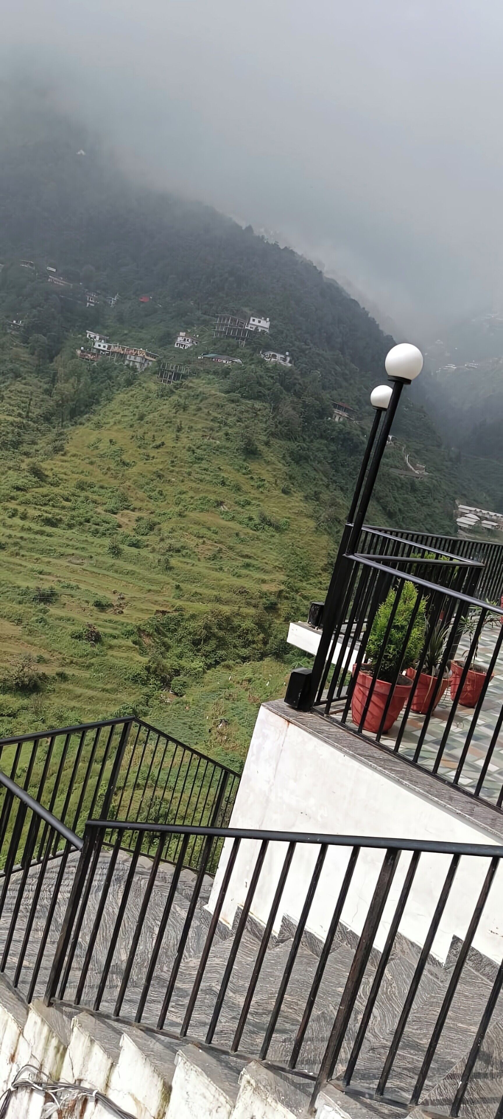 Eine Treppe mit Metallgeländer führt zu einem Balkon mit Blick auf eine gebirgige Landschaft.