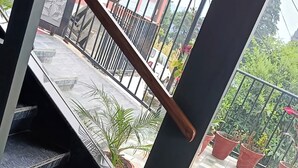 A modern interior with a black and white tiled floor, a white sofa, and a view of the outside balcony with potted plants. - Rubystone Mussoorie A Leisure Resort (Dehradun)