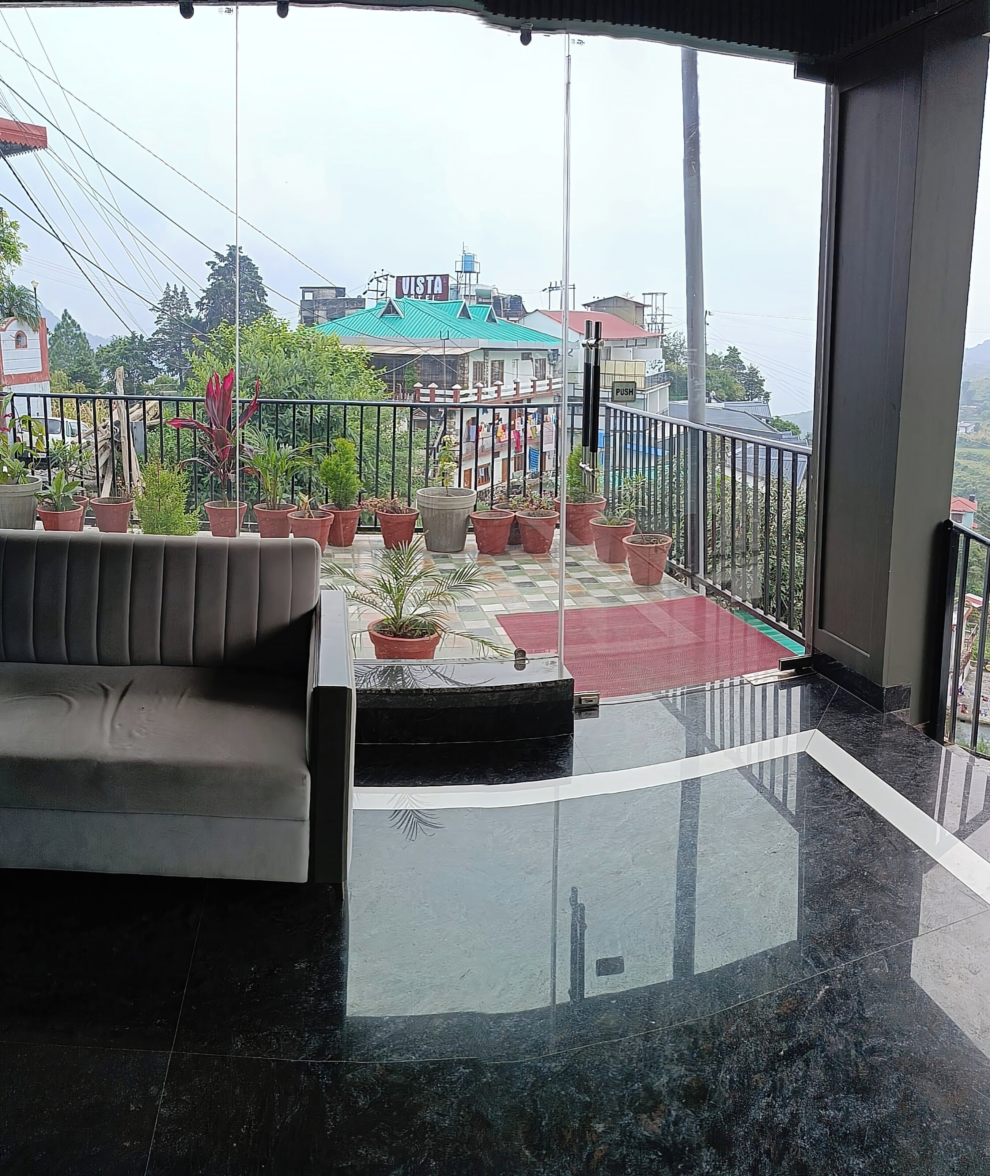 Ein Balkon mit einer Couch, Topfpflanzen und einer roten Matte.