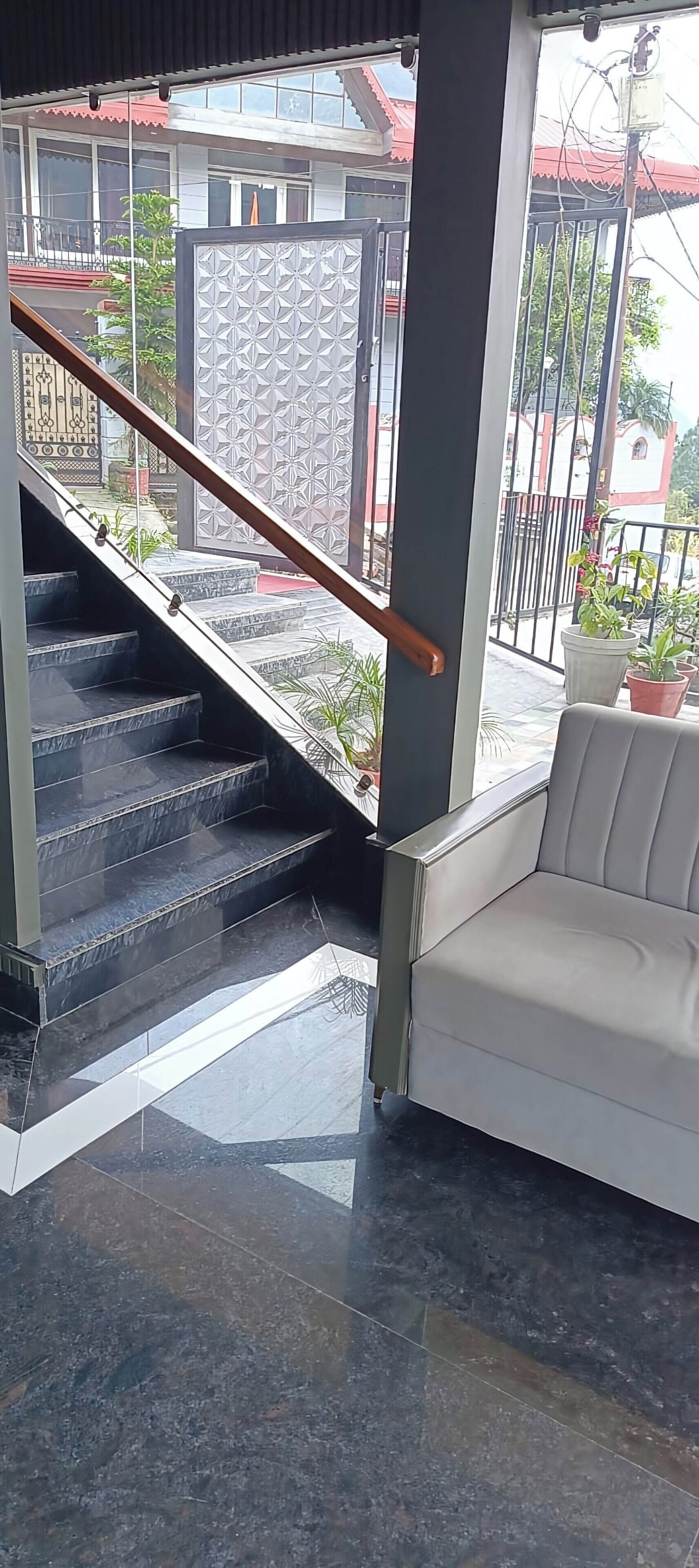 A staircase with a wooden handrail leading to a balcony with a white sofa.