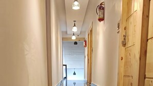 A long, polished hallway with wooden doors on one side and a fire extinguisher on the wall. - Rubystone Mussoorie A Leisure Resort (Dehradun)
