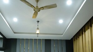 A hotel room with two beds, a ceiling fan, a chandelier, and a glass coffee table. - Rubystone Mussoorie A Leisure Resort (Dehradun)