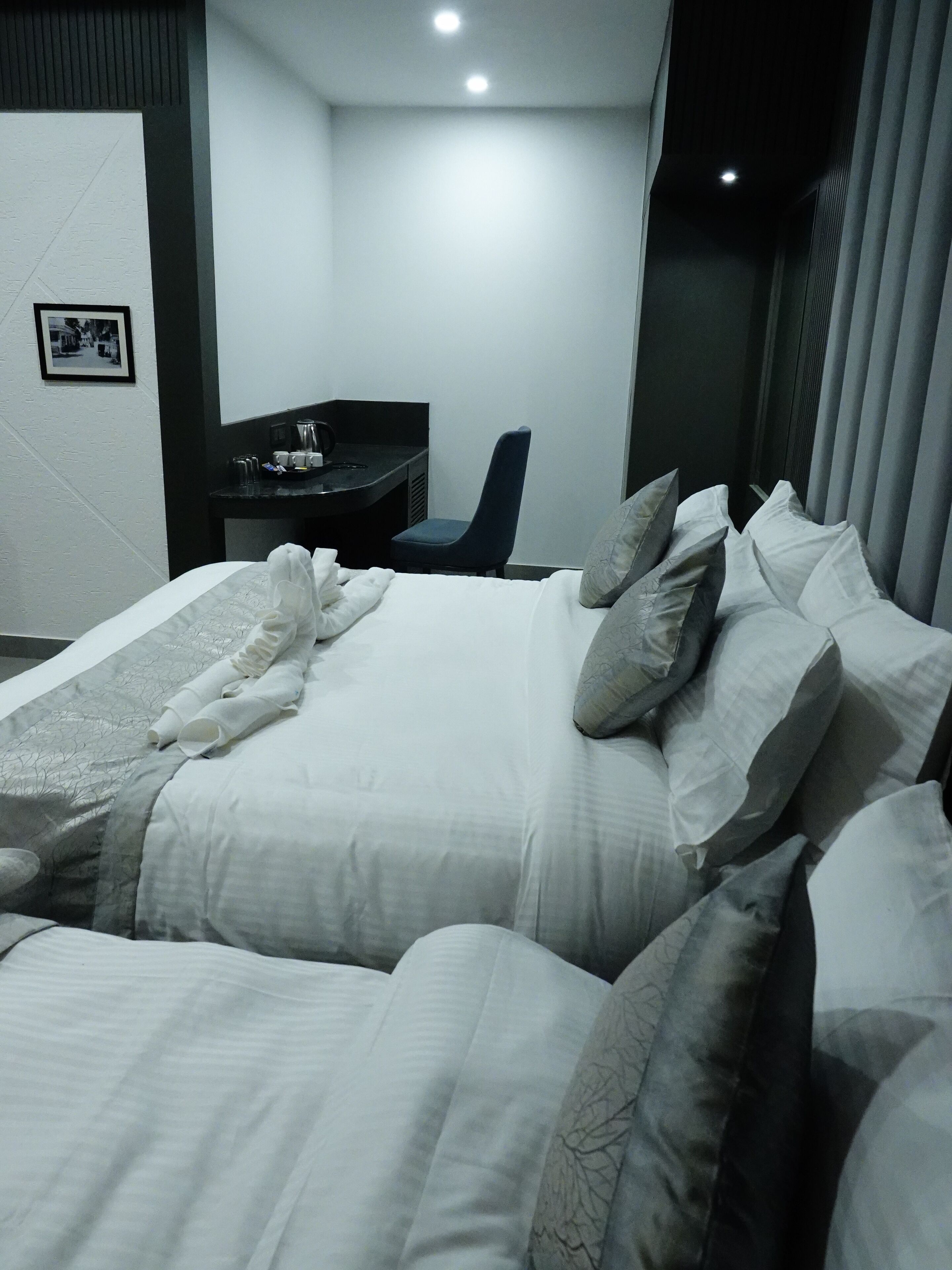 A hotel room with two beds, a desk, and a chair.