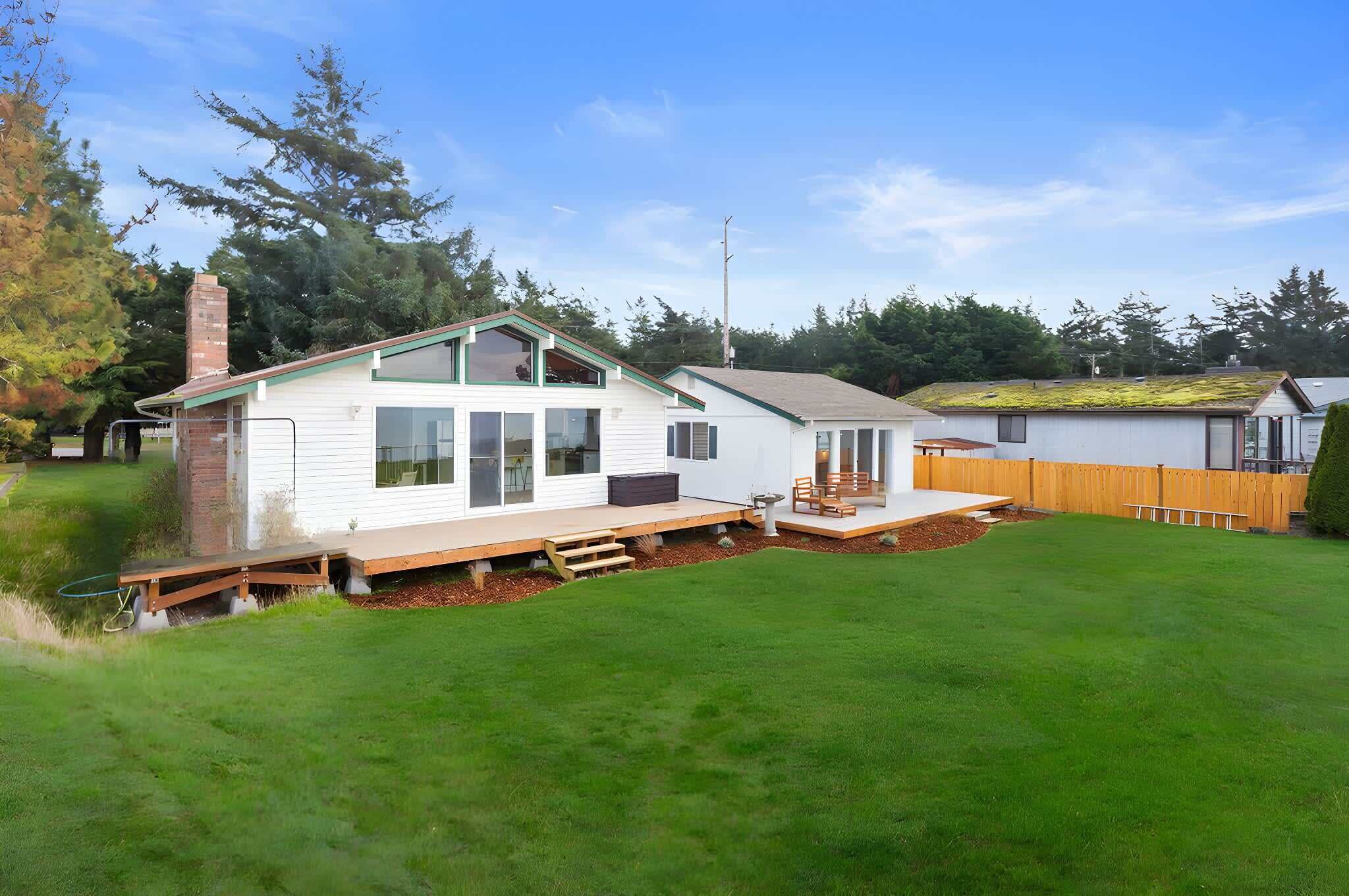 Une maison de plain-pied avec une terrasse à l’avant, un patio couvert et une cour arrière clôturée.