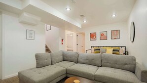 A living room with a sectional sofa, a coffee table, and a bed with a headboard. - Cozy Getaway Retreat 4BR At Northglenn (Northglenn)