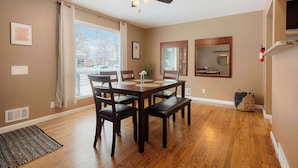 A dining area with a table, chairs, a ceiling fan, and a window with curtains. - Cozy Getaway Retreat 4BR At Northglenn (Northglenn)