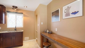 A kitchen with dark wooden cabinets, a granite countertop, a window with frosted glass, and a bar area with stools. - Cozy Getaway Retreat 4BR At Northglenn (Northglenn)