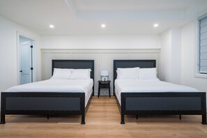 Habitación doble con dos camas, una mesita de noche y una puerta.