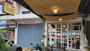 Un hostal con una persiana baja, una moto estacionada y plantas en macetas al frente.