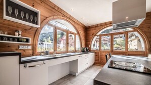 Eine moderne Küche mit Holzverkleidung, großen Fenstern und einer zentralen Kochinsel.