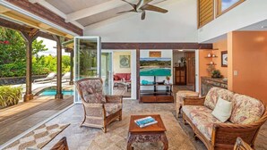 A spacious living area with a pool view, wicker furniture, and a ceiling fan. - Lei Ohana - Private Pool, Separate Guest House (Koloa)