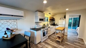 Cocina compacta con comedor, microondas, estufa y una pequeña mesa.
