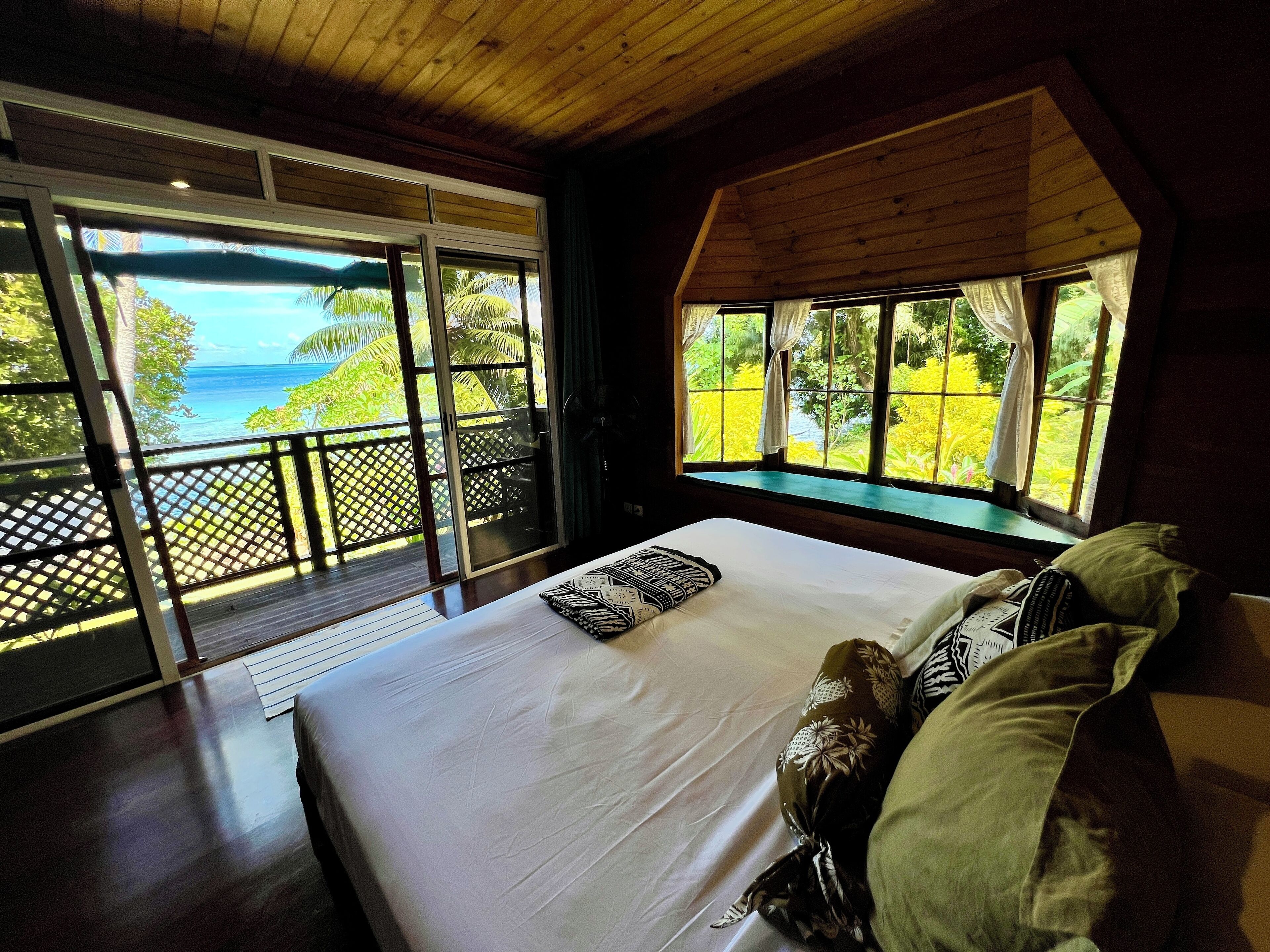 Une chambre avec un grand lit, une vue sur l’océan et un plafond en bois.