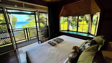 Une chambre avec un grand lit, une vue sur l’océan et un plafond en bois.