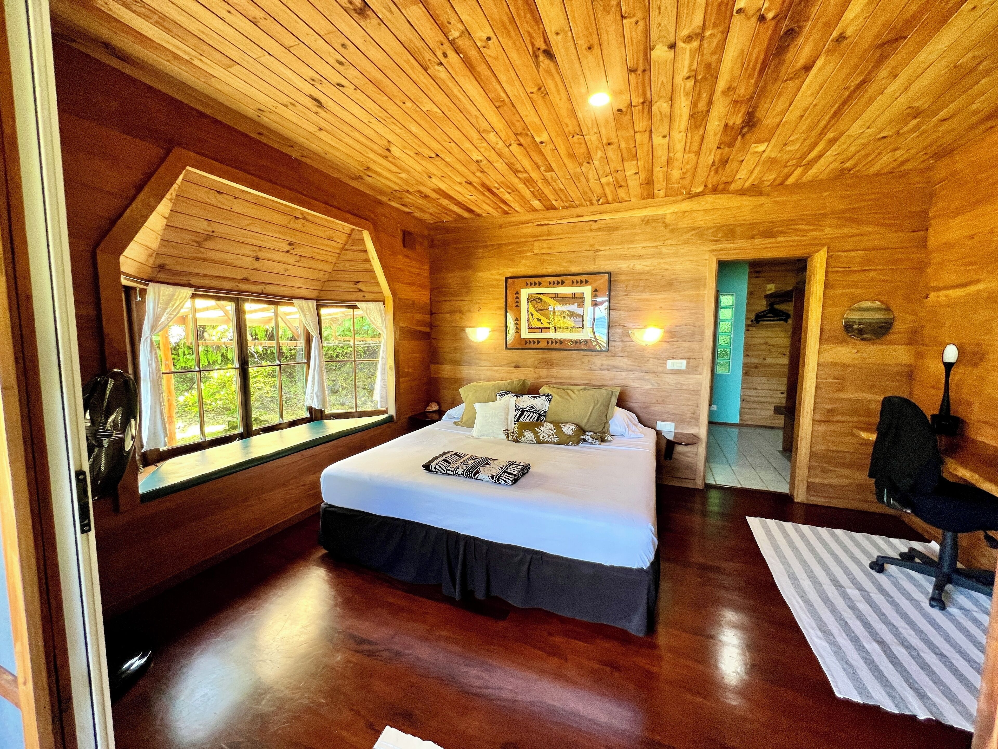 Une pièce en bois avec un lit, une fenêtre et une porte.