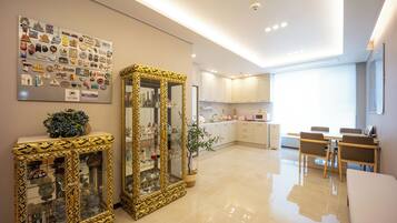 A modern kitchen with white cabinets, a dining area with wooden chairs, and a decorative mirror with a gold frame.