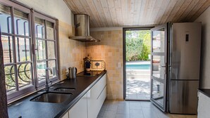 A modern kitchen with a stainless steel sink, a built-in oven, and a large refrigerator.