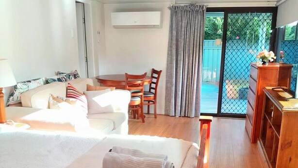 A hotel room with two beds, a dining area, a wooden dresser, and a sliding glass door to the outside. - Convenient spot Gosford /near M1HW,CBD,Hospital,Stadium,water view,fishing,pet (West Gosford)