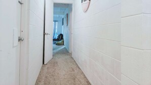 A narrow hallway with white walls and a carpeted floor, leading to a room with a bed and a window. - 2 bedroom cosy guest house in North shore (Auckland)