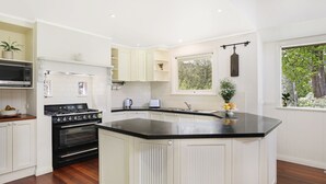A modern kitchen with white cabinetry, a black countertop, and a built-in stove.