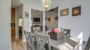 Un espace repas comprenant une table, des chaises, un lustre et des œuvres d’art accrochées aux murs.