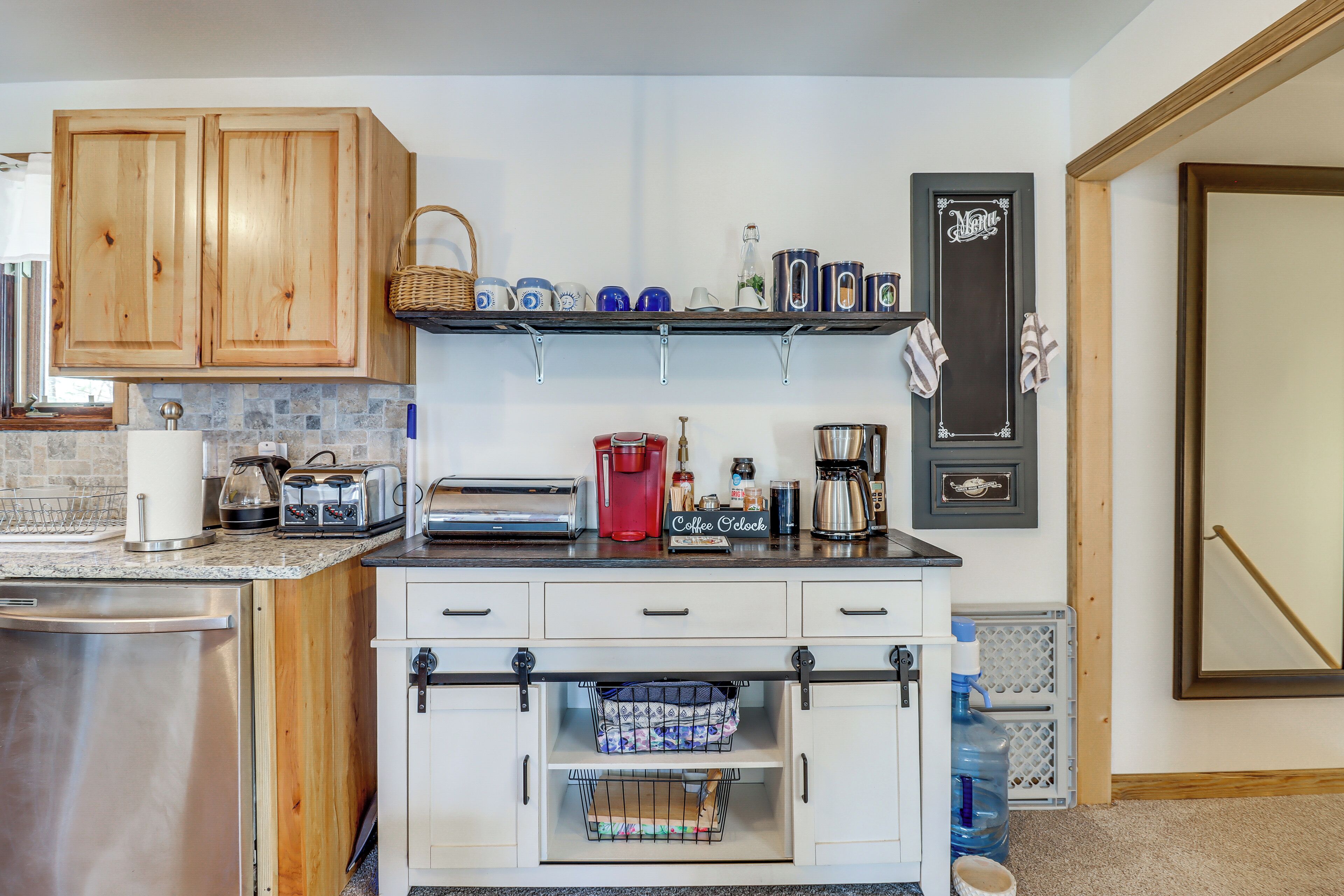 Una cocina con armarios de madera, espacio para café y dispensador de agua.