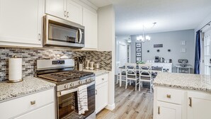 A modern kitchen with white cabinetry, a stainless steel stove, and a microwave. - Indiana Dunes Home w/ Gas Grill: 1 Mi to Beach! (Michigan City)