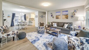 A spacious living room with a large sofa, a coffee table, and a dining area with a table and chairs. - Indiana Dunes Home w/ Gas Grill: 1 Mi to Beach! (Michigan City)