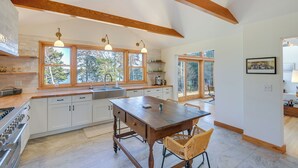 A modern kitchen with white cabinets, a wooden dining table, and pendant lights. - Chic Addison Home w/ Fire Pit on 8 Private Acres! (Addison)