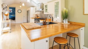 A modern kitchen with a wooden island, white cabinets, and a large window. - Fountainhall Townhouse Aberdeen City (Aberdeen)