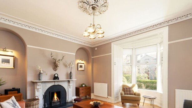 A living room with a fireplace, a sofa, a coffee table, and a chandelier. - Fountainhall Townhouse Aberdeen City (Aberdeen)