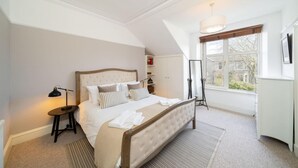 A bedroom with a large bed, a bedside table, a floor lamp, a window with a view, and a radiator. - Fountainhall Townhouse Aberdeen City (Aberdeen)