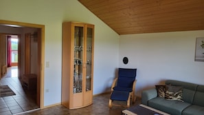 Un salon avec un meuble en bois, un fauteuil bleu rembourré et un canapé vert.