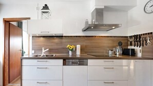 Una cucina moderna con mobili bianchi, un piano di lavoro in legno, una lavastoviglie e un orologio a parete.