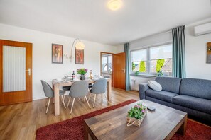 Moderni olohuone, jossa on ruokailutila, sohva ja sohvapöytä.