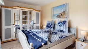 Un dormitorio con cama, armario, mesita de noche y un cuadro de un faro.