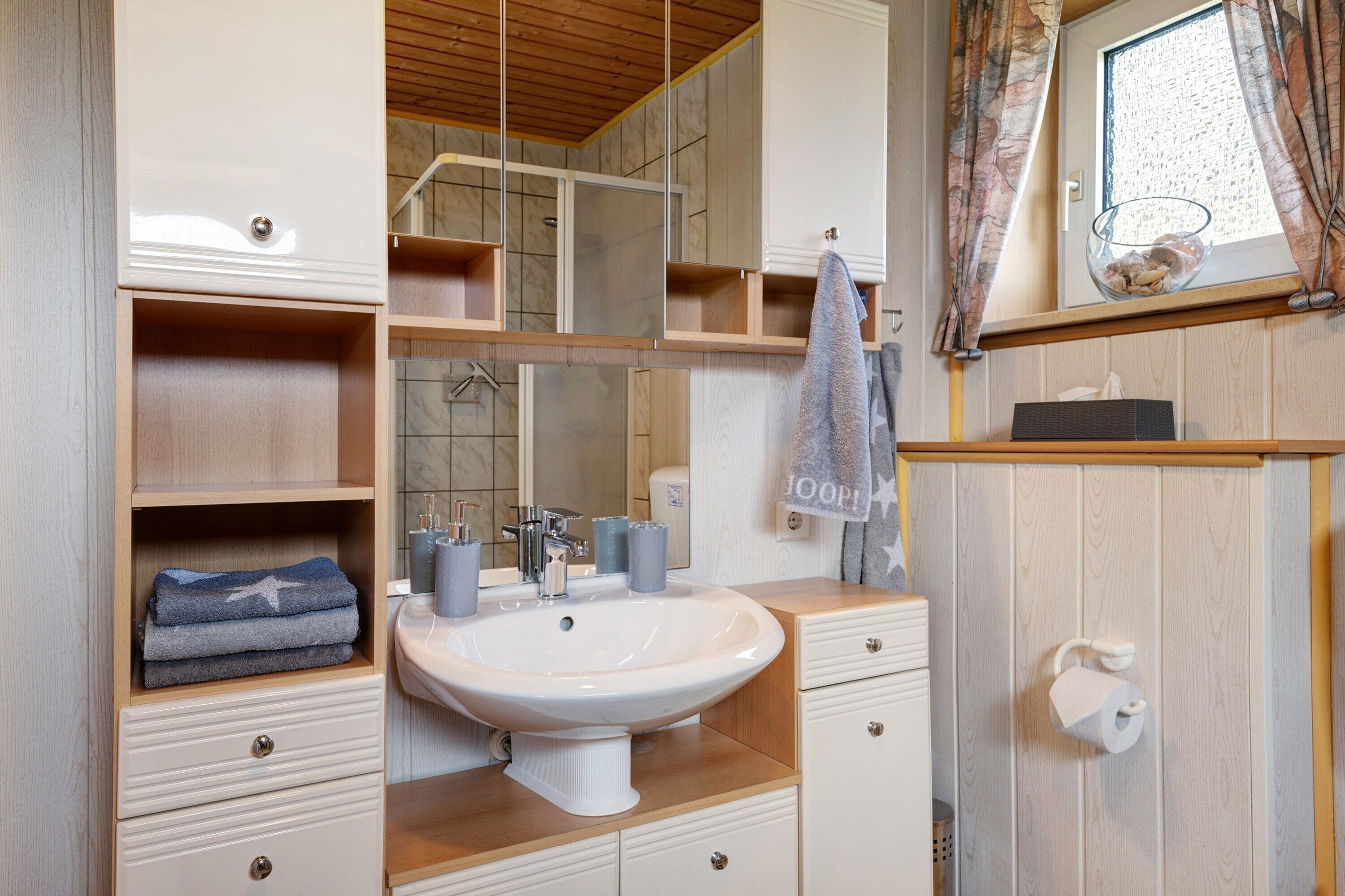 A bathroom with a sink, mirror, towel rack, and wooden cabinets.
