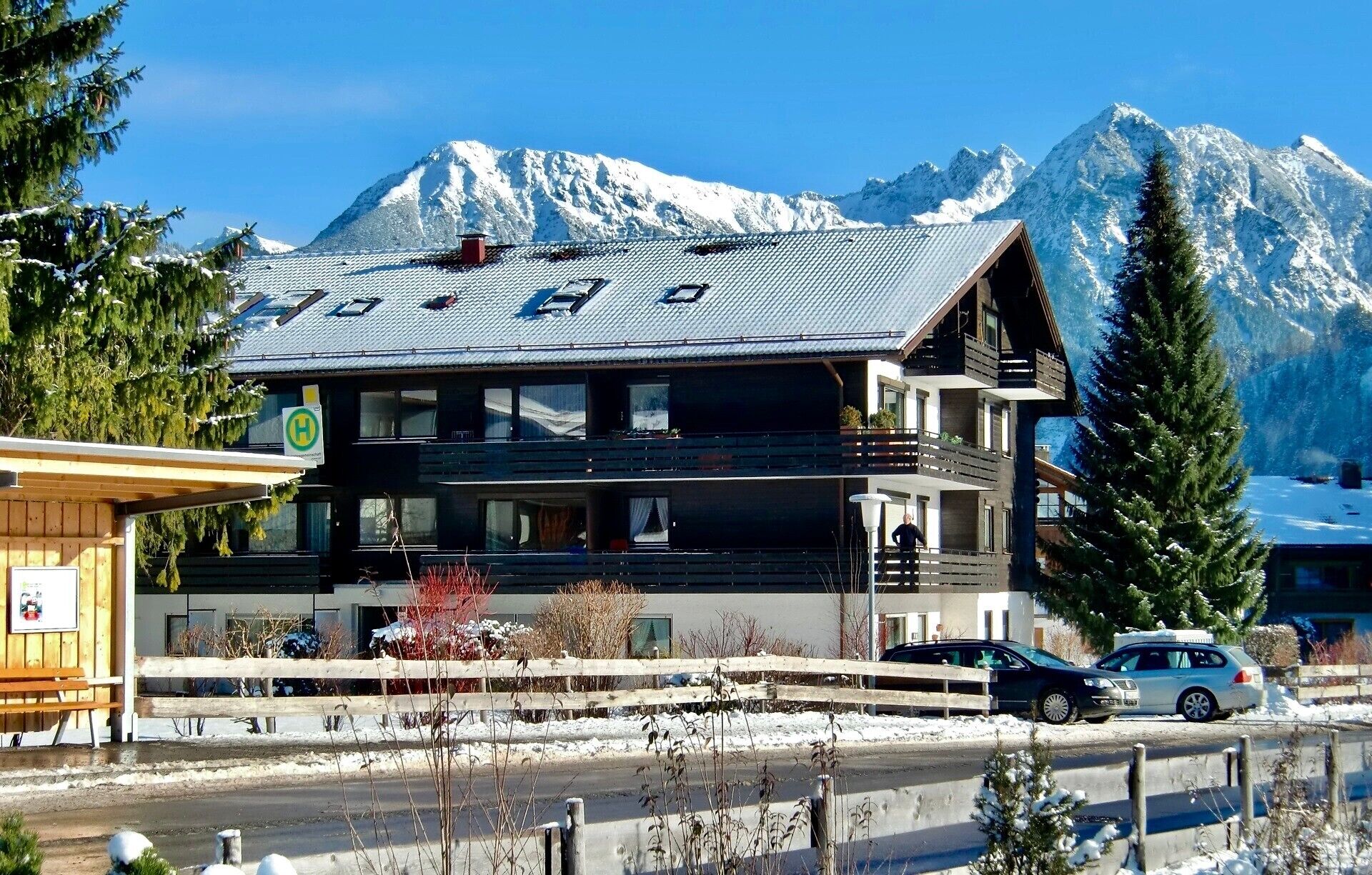 A two-story lodge with a ski slope view, a wooden exterior, and a visible H sign indicating a hotel.