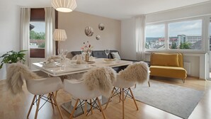 Un comedor moderno con una mesa dispuesta para cuatro personas, un sofá y vistas a la ciudad.